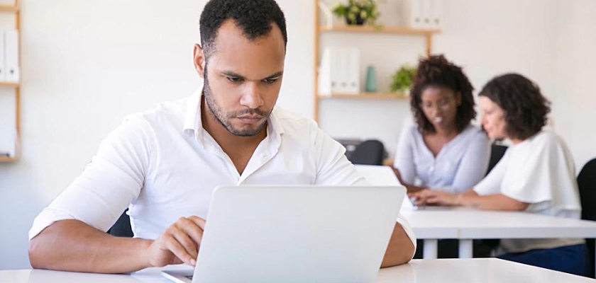 Impiegato maschio concentrato che utilizza il computer portatile in ufficio – Come iniziare trading senza rischi